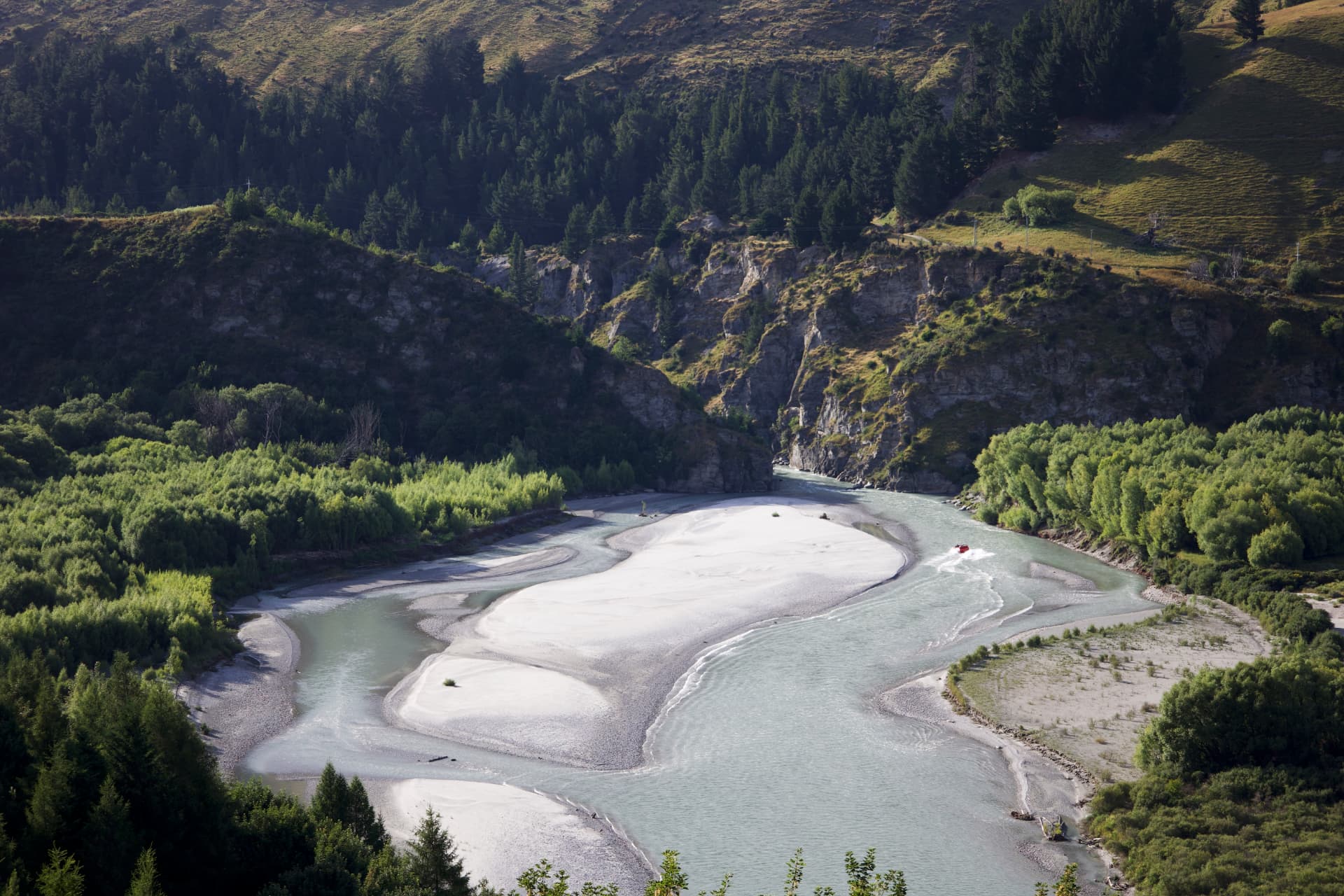 A pale winding river and sandbars among green hills near Queenstown, New Zealand