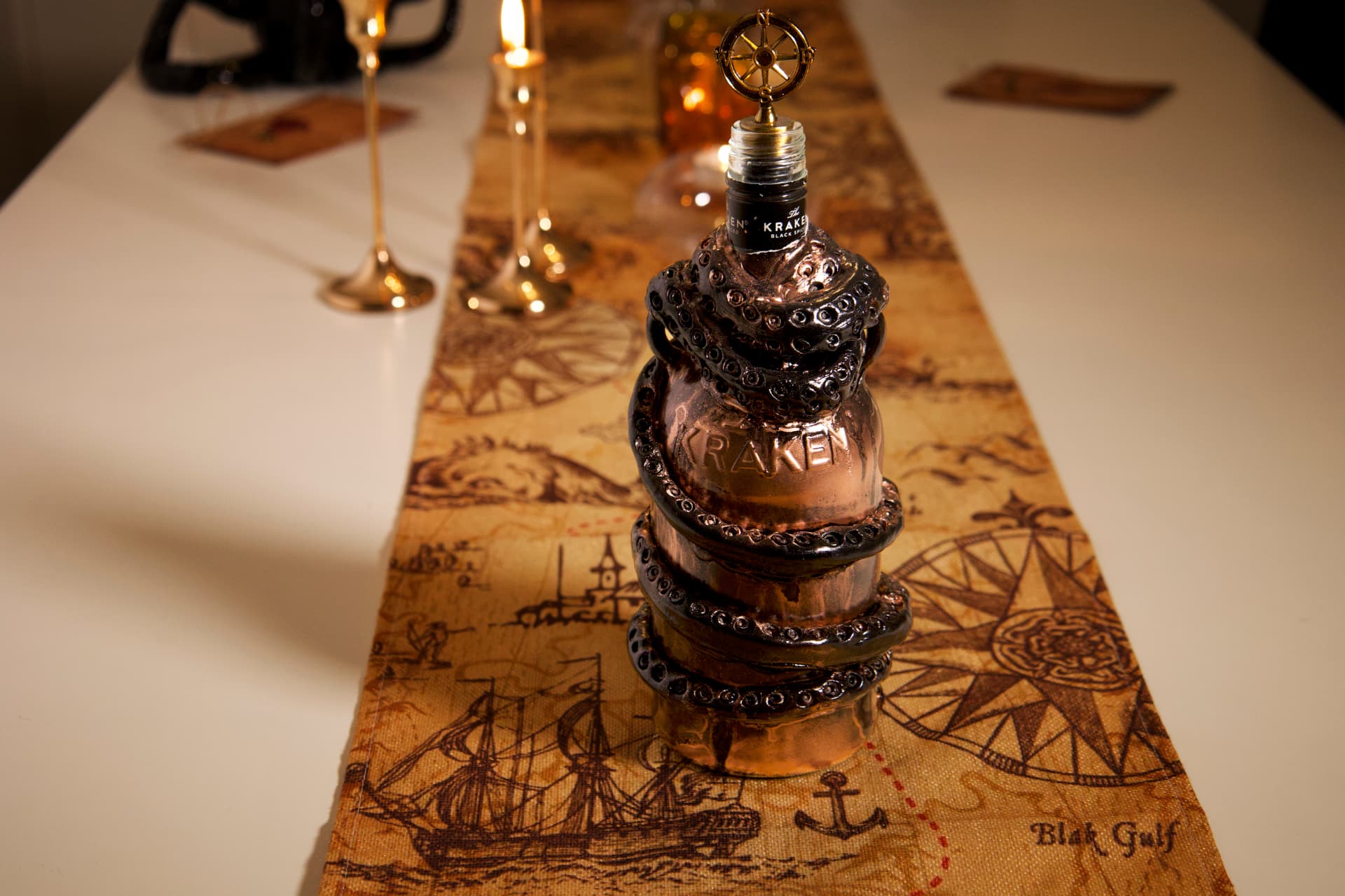 A copper-colored Kraken rum bottle sculpted with dark tentacles and aged patina, displayed on a vintage map table runner with candlelight.