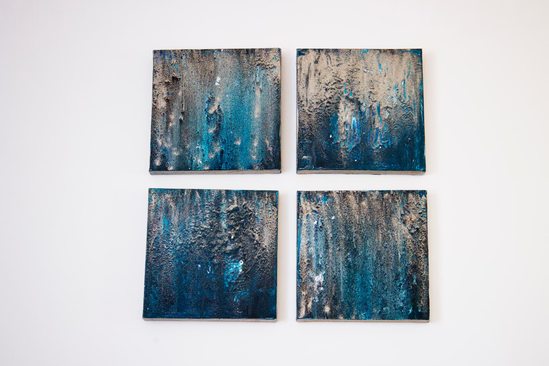 A four-panel acrylic painting in golden and white winter tones.