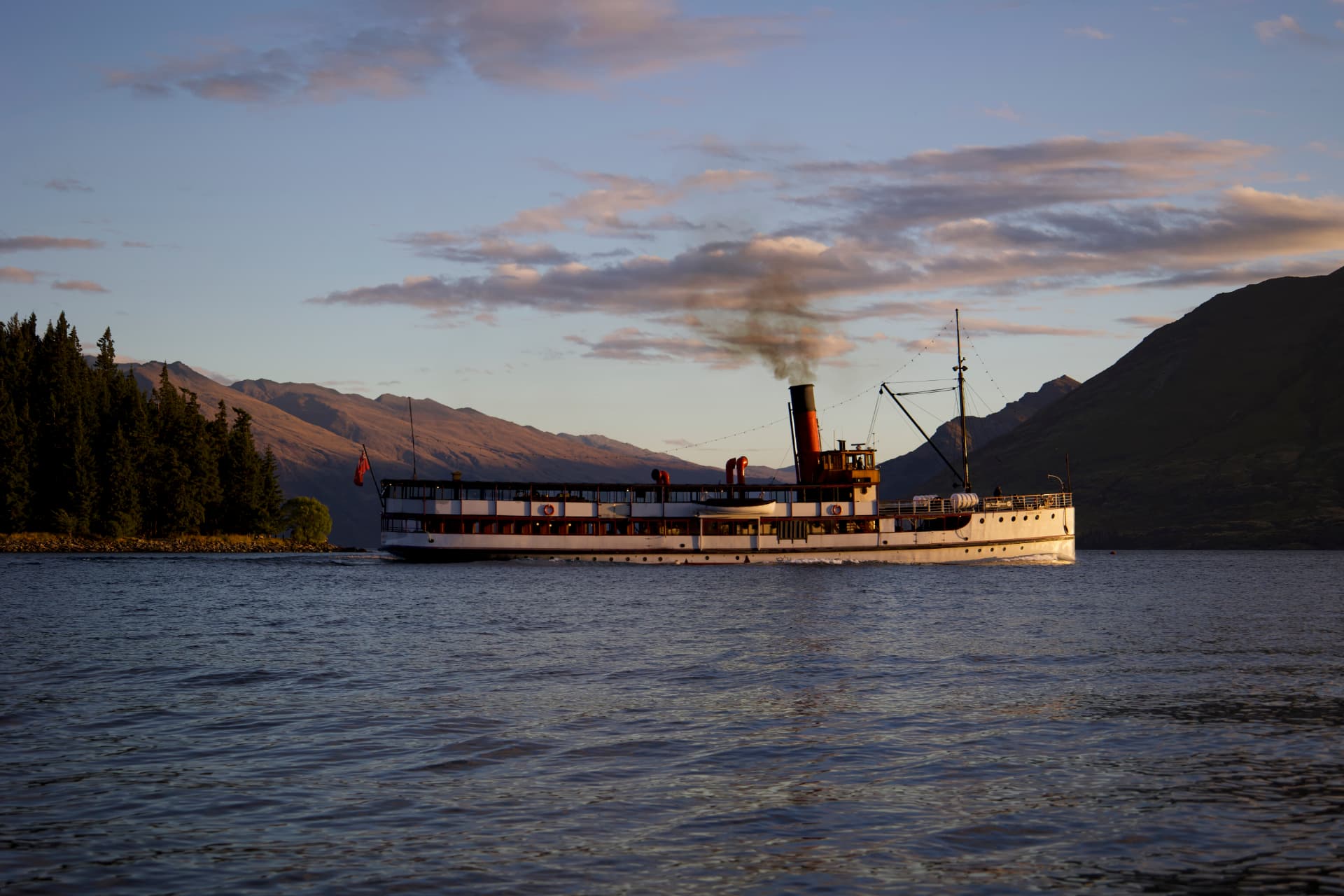 The TSS Earnslaw steamship cruising on Lake Wakatipu at sunset with mountains behind, Queenstown, New Zealand